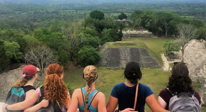 Five international students overlook a scenic field with a pyramid