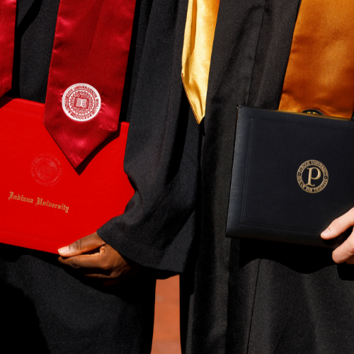 Close up students in graduation robes holding diplomas from Purdue and IU