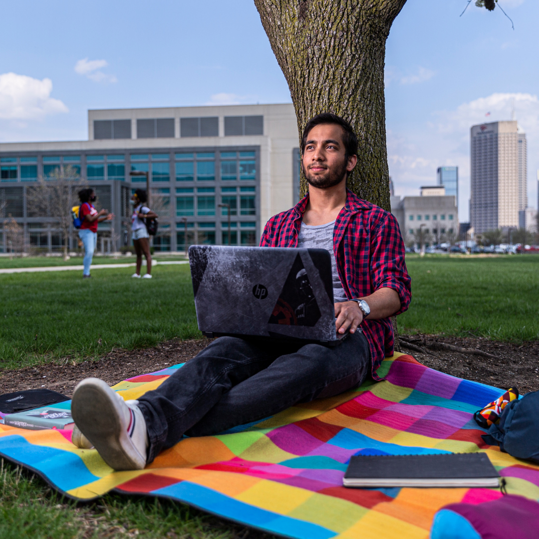 Student with laptop sitting outside